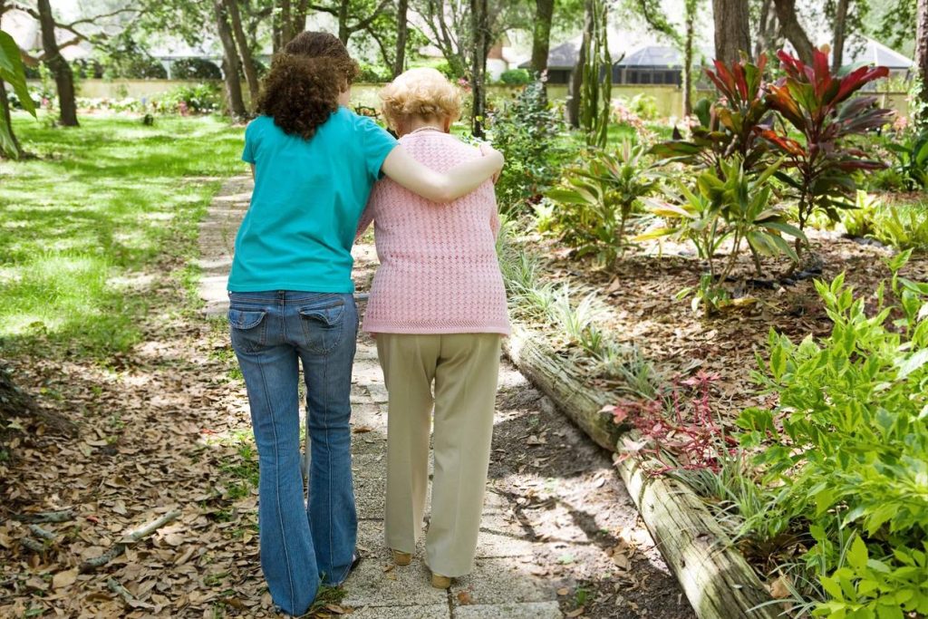 CARE-GIVER HELPING A WOMAN WITH ALZHEIMER'S WALK