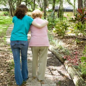 CARE-GIVER HELPING A WOMAN WITH ALZHEIMER'S WALK
